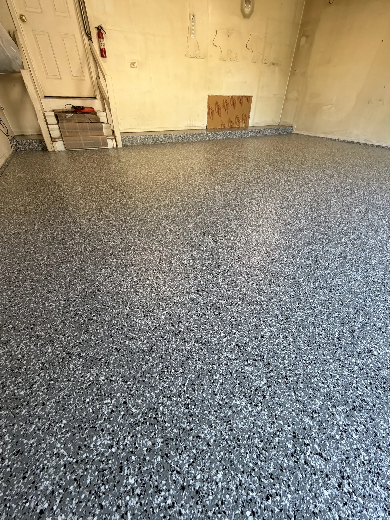 Grey and white flake coated garage floor running wall to wall under a clear topcoat