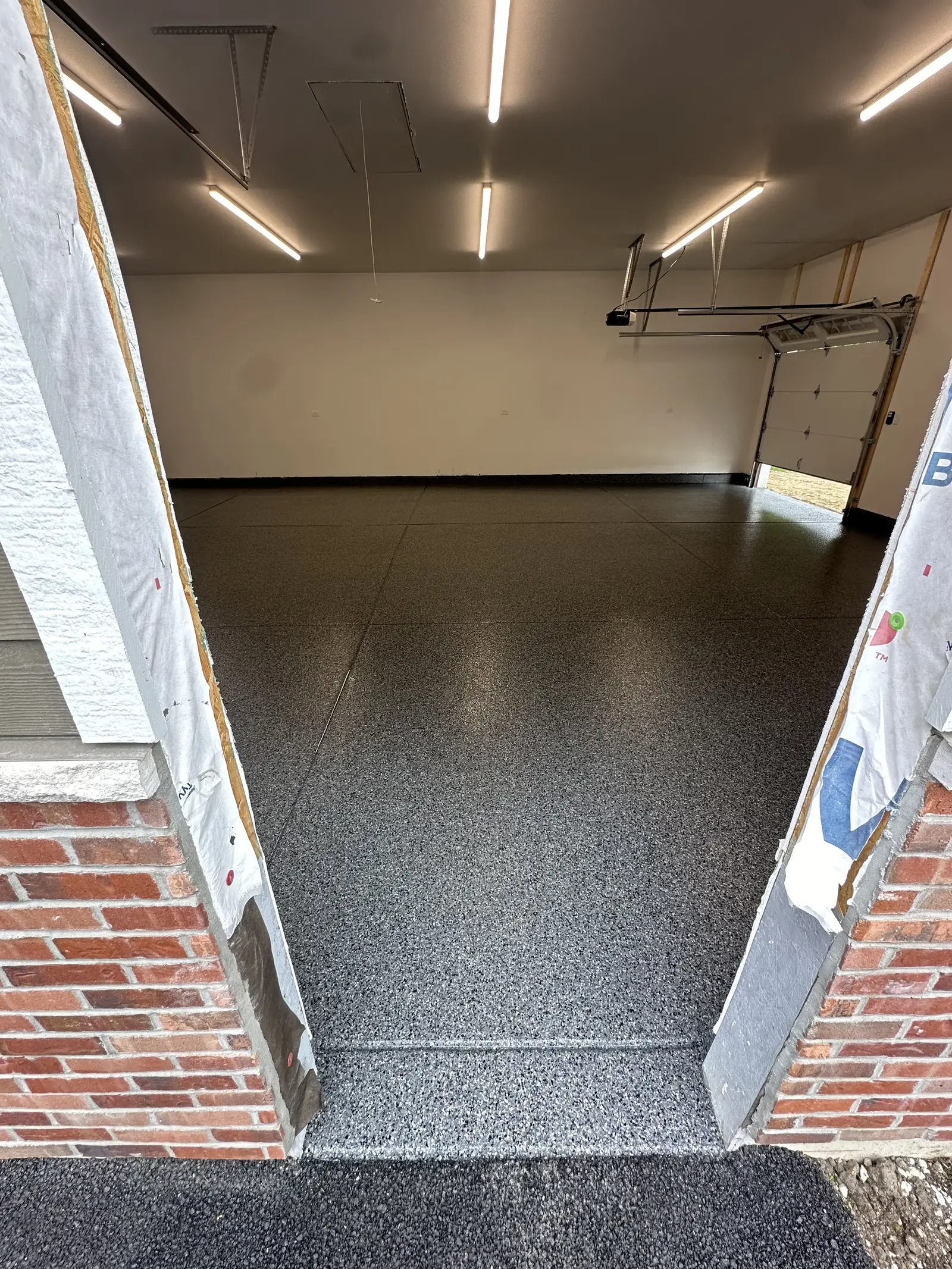 Grey flake coated floor meeting a brick step at a garage entry