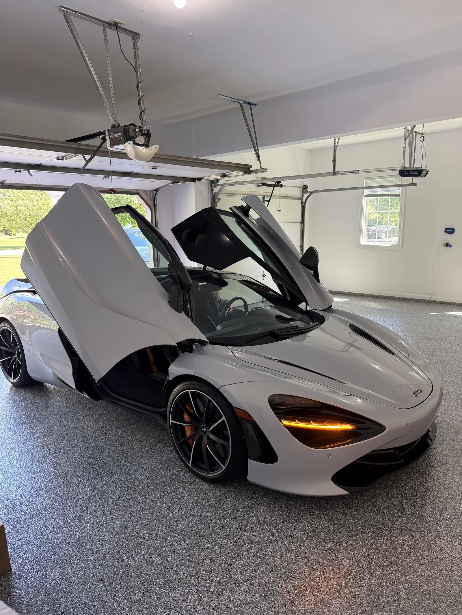 White McLaren with its doors up on a flake coated garage floor